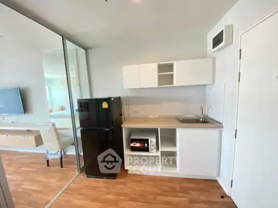 Modern compact kitchen with sleek design and wooden flooring in a bright apartment.