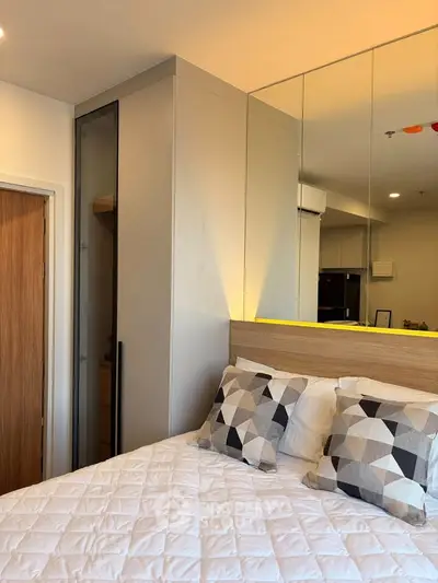 Modern bedroom with stylish decor and mirrored wardrobe in a cozy apartment.