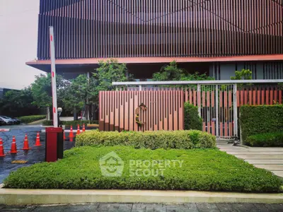 Modern building entrance with lush greenery and security gate