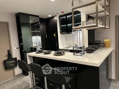 Modern kitchen with sleek black cabinetry and open layout, featuring a stylish breakfast bar and contemporary decor.