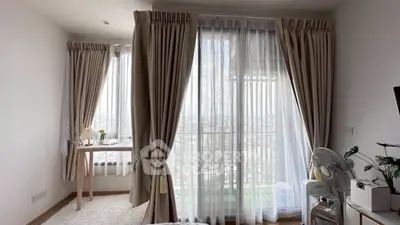 Bright bedroom with large windows and elegant curtains offering a stunning city view.