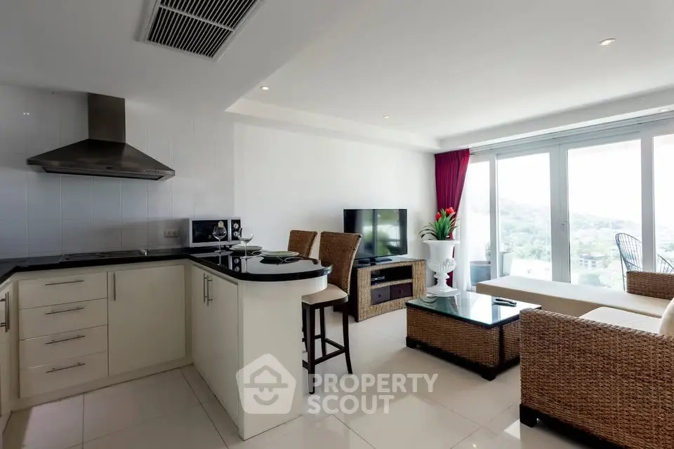 Modern open-layout living room with kitchen, featuring panoramic windows and stylish wicker furniture.