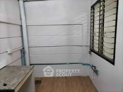 Compact utility room with tiled floor and window, ideal for storage or laundry setup.
