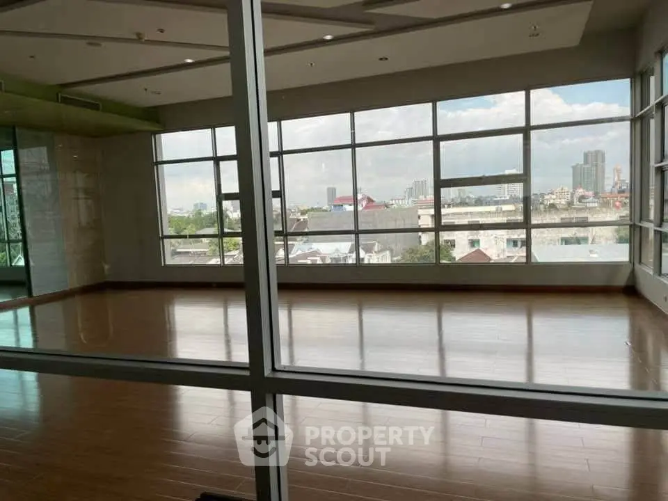 Spacious empty room with large windows offering city views, perfect for customization.
