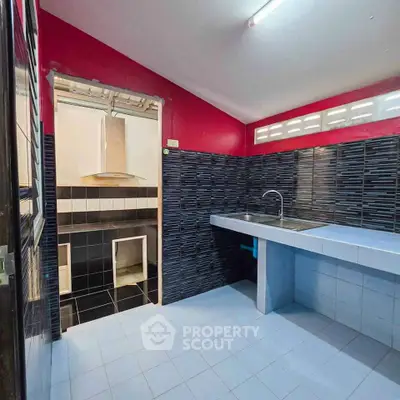 Modern kitchen with sleek black and red tiles, featuring a spacious countertop and open layout.