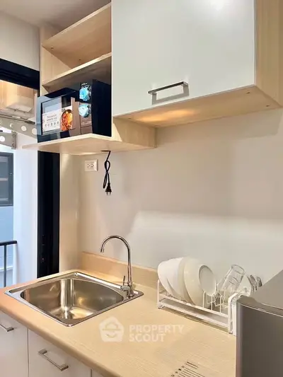 Modern kitchen with sleek cabinetry, stainless steel sink, and microwave, perfect for urban living.