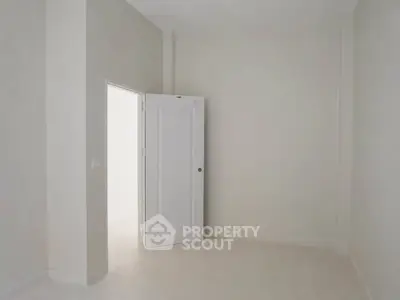Minimalist empty room with open door and white walls, ideal for customization.