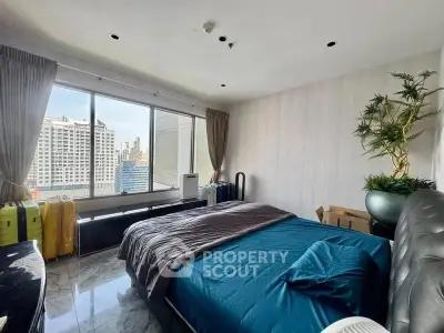 Spacious bedroom with city view and modern decor in high-rise apartment.