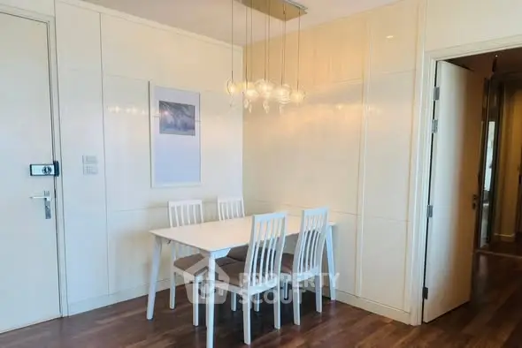 Modern dining area with elegant lighting and wooden flooring in a stylish apartment.