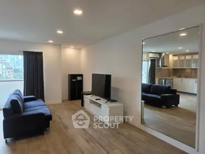 Spacious modern living room with sleek furniture and large mirror, ideal for urban living.