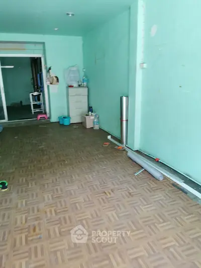 Spacious interior with parquet flooring and mint green walls, ideal for customization.