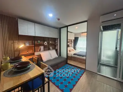 Modern studio apartment with cozy living area and stylish bedroom separated by glass partition.