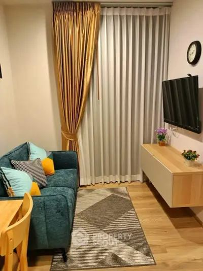 Cozy living room with modern decor, featuring a plush blue sofa, wall-mounted TV, and elegant curtains.