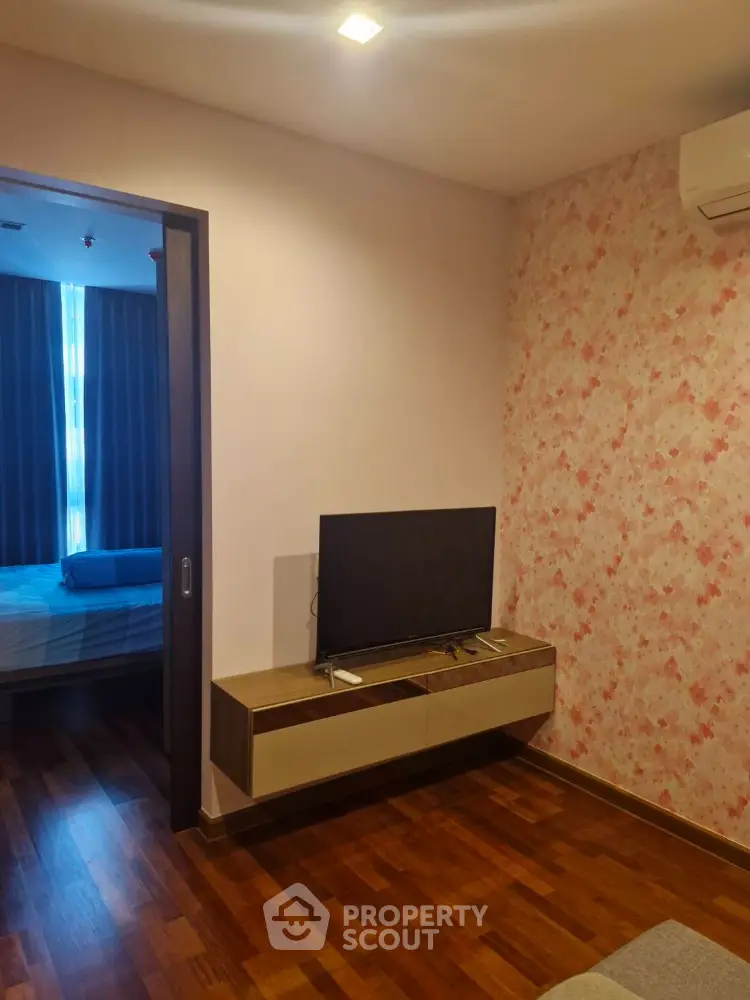 Cozy bedroom with wooden flooring and wall-mounted TV, perfect for modern living.