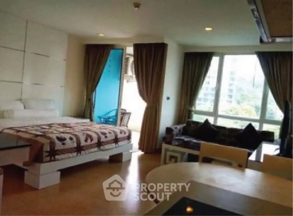 Spacious studio apartment with modern decor and large windows offering natural light.