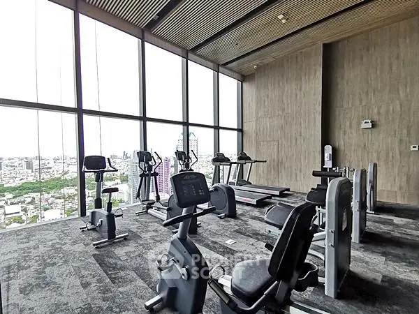 Spacious gym with panoramic city views and modern fitness equipment.