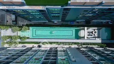 Stunning aerial view of modern apartment complex with central swimming pool and lush greenery.
