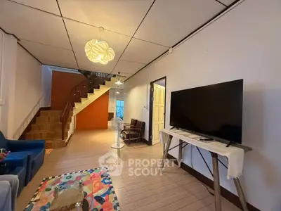 Spacious living room with modern decor and large TV, featuring a unique staircase design.