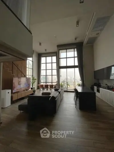 Spacious modern living room with high ceilings and large windows offering city views.