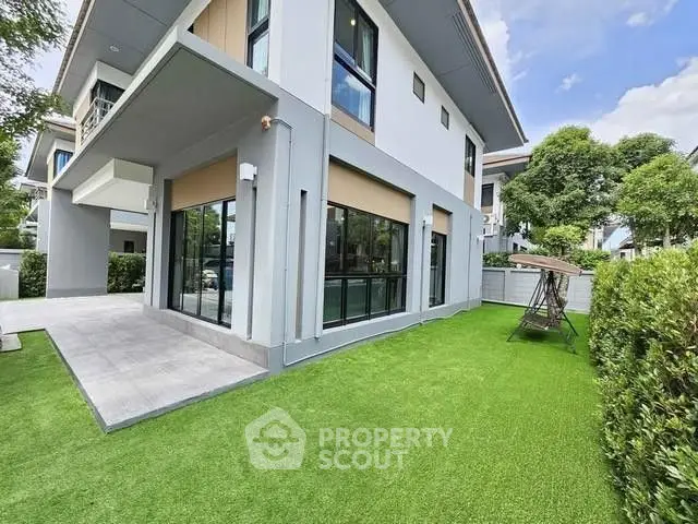 Modern two-story house with lush green lawn and large windows, perfect for family living.
