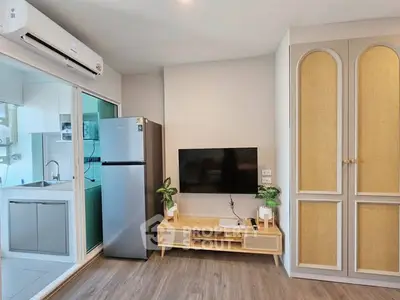 Modern living room with sleek design, featuring a TV, fridge, and stylish cabinetry.