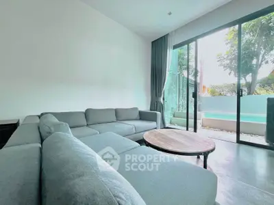 Spacious living room with modern gray sofa and pool view through sliding glass doors.