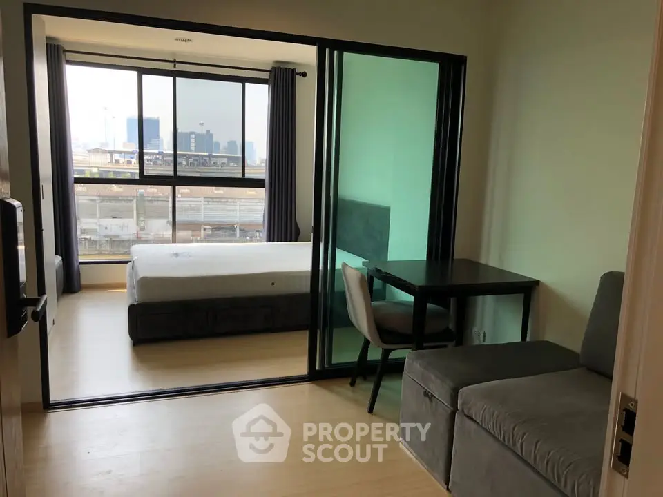 Modern studio apartment with glass partition and city view, featuring a cozy living area and bedroom.