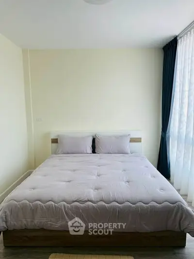 Spacious bedroom with large bed and natural light from floor-to-ceiling windows.
