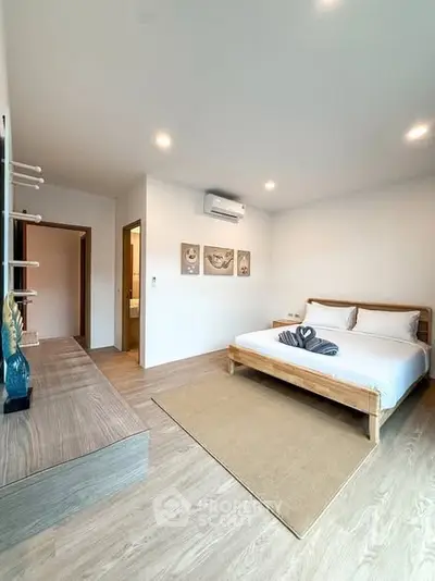 Spacious modern bedroom with wooden flooring and stylish decor