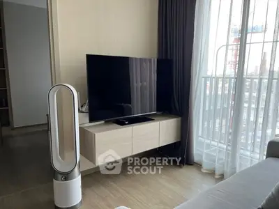 Spacious living room with modern furnishings, large windows allowing ample natural light, and a sleek flat-screen TV, perfect for comfortable urban living.