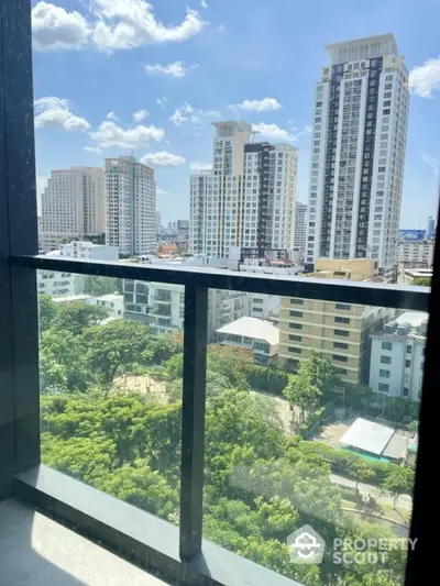 Stunning cityscape view from high-rise balcony with lush greenery and modern buildings.