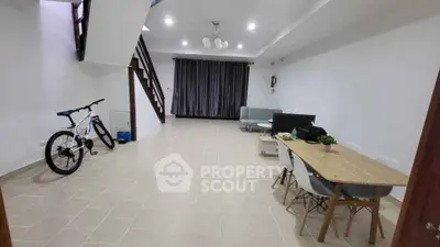 Spacious living room with modern decor and dining area, featuring a bicycle and elegant lighting.