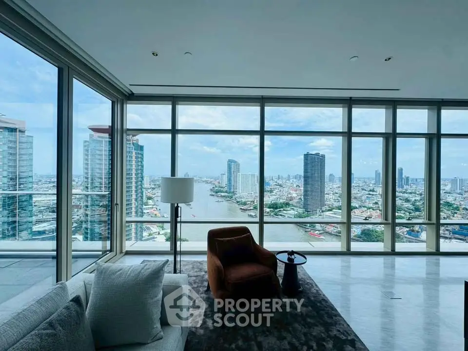 Luxurious living room with panoramic city and river views, featuring modern furniture and floor-to-ceiling windows.