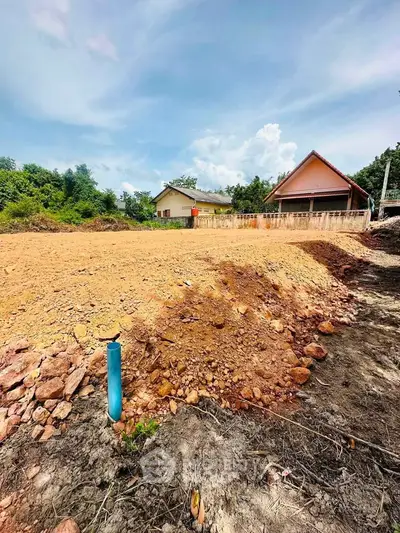 Spacious land plot with potential for development, surrounded by lush greenery and clear skies.