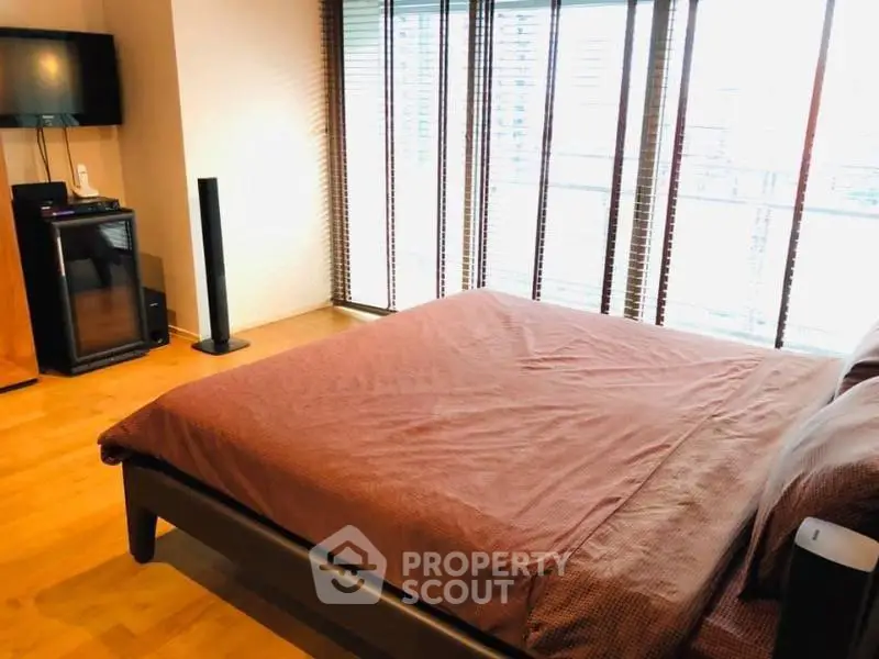 Spacious bedroom with large windows and modern decor in a luxury apartment.