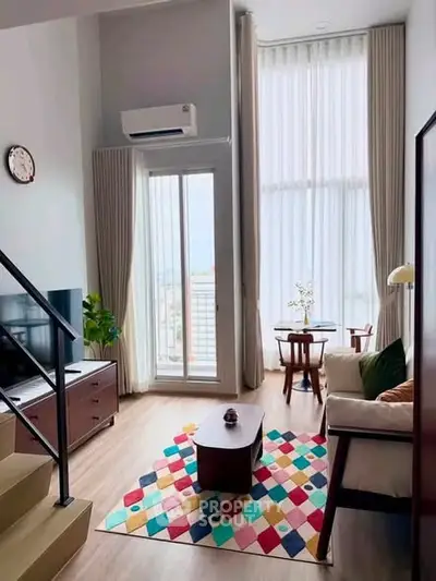Stylish modern living room with high ceilings and colorful decor in a bright apartment.