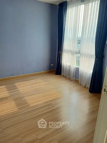 Spacious empty room with large window and wooden flooring, perfect for customization.