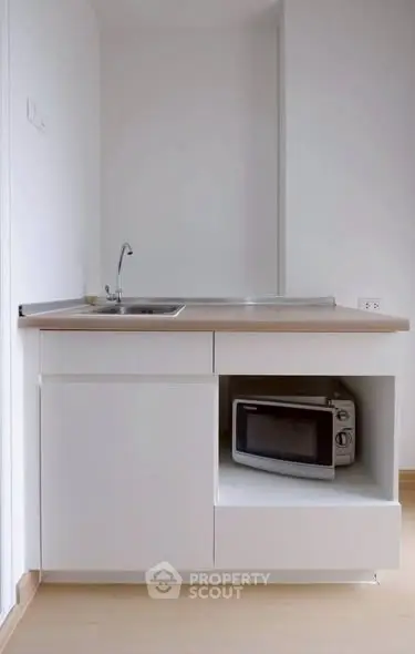 Compact modern kitchen with sleek white cabinetry and built-in microwave