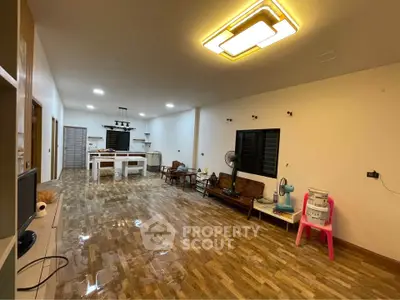 Spacious open-plan living area with modern lighting and wooden flooring, ideal for family gatherings.