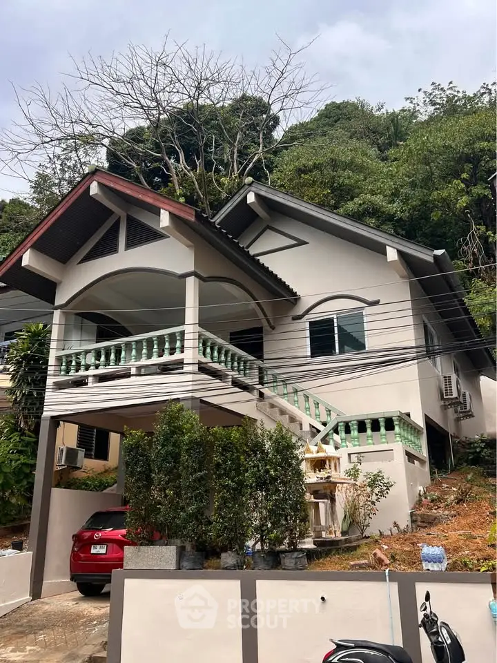 Charming hillside house with elevated porch and lush greenery, perfect for serene living.