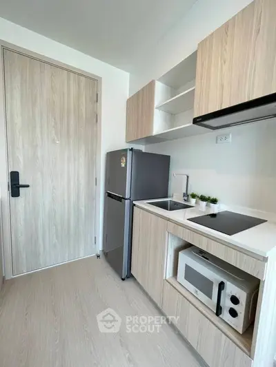 Modern compact kitchen with sleek appliances and wooden cabinetry in a stylish apartment.