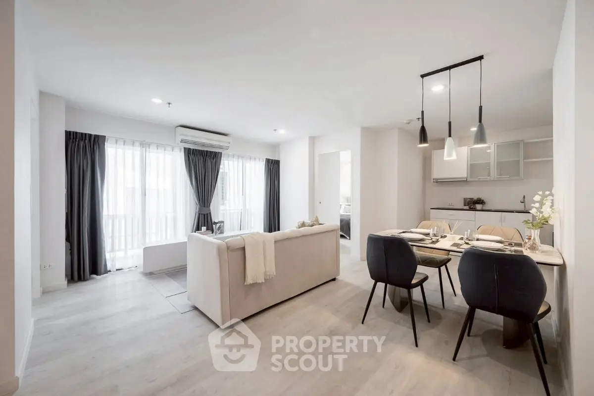 Spacious modern living room with dining area and open kitchen in elegant apartment.