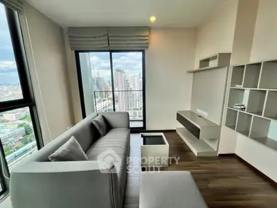 Modern living room with city view, featuring sleek furniture and large windows in a high-rise apartment.