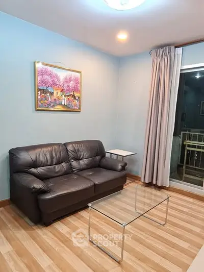 Cozy living room with leather sofa and glass coffee table, perfect for relaxation.