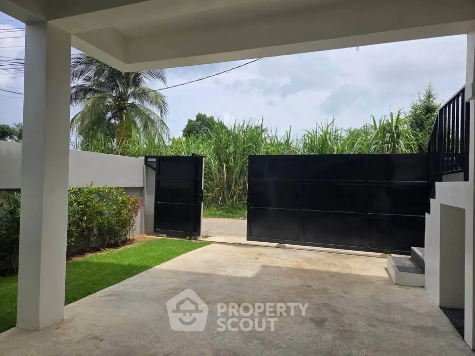 Spacious modern driveway with sleek black gate and lush greenery, perfect for secure and stylish home entrance.