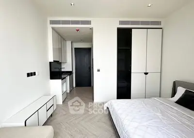 Modern bedroom with sleek design and integrated kitchenette in a contemporary apartment.