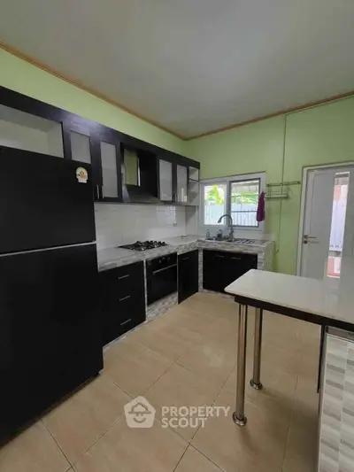 Modern kitchen with black cabinets and gas stove in a spacious layout.