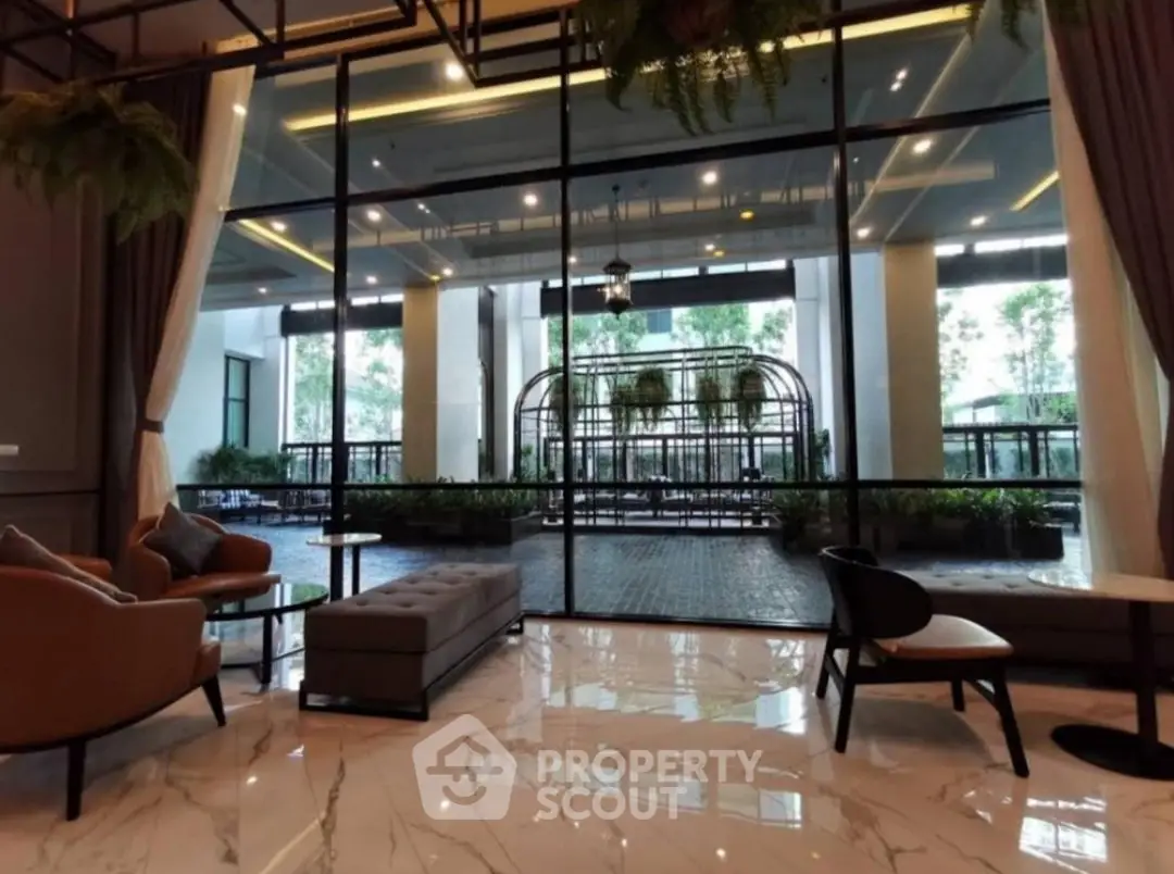 Luxurious lobby with modern seating and large glass windows overlooking a lush garden area.
