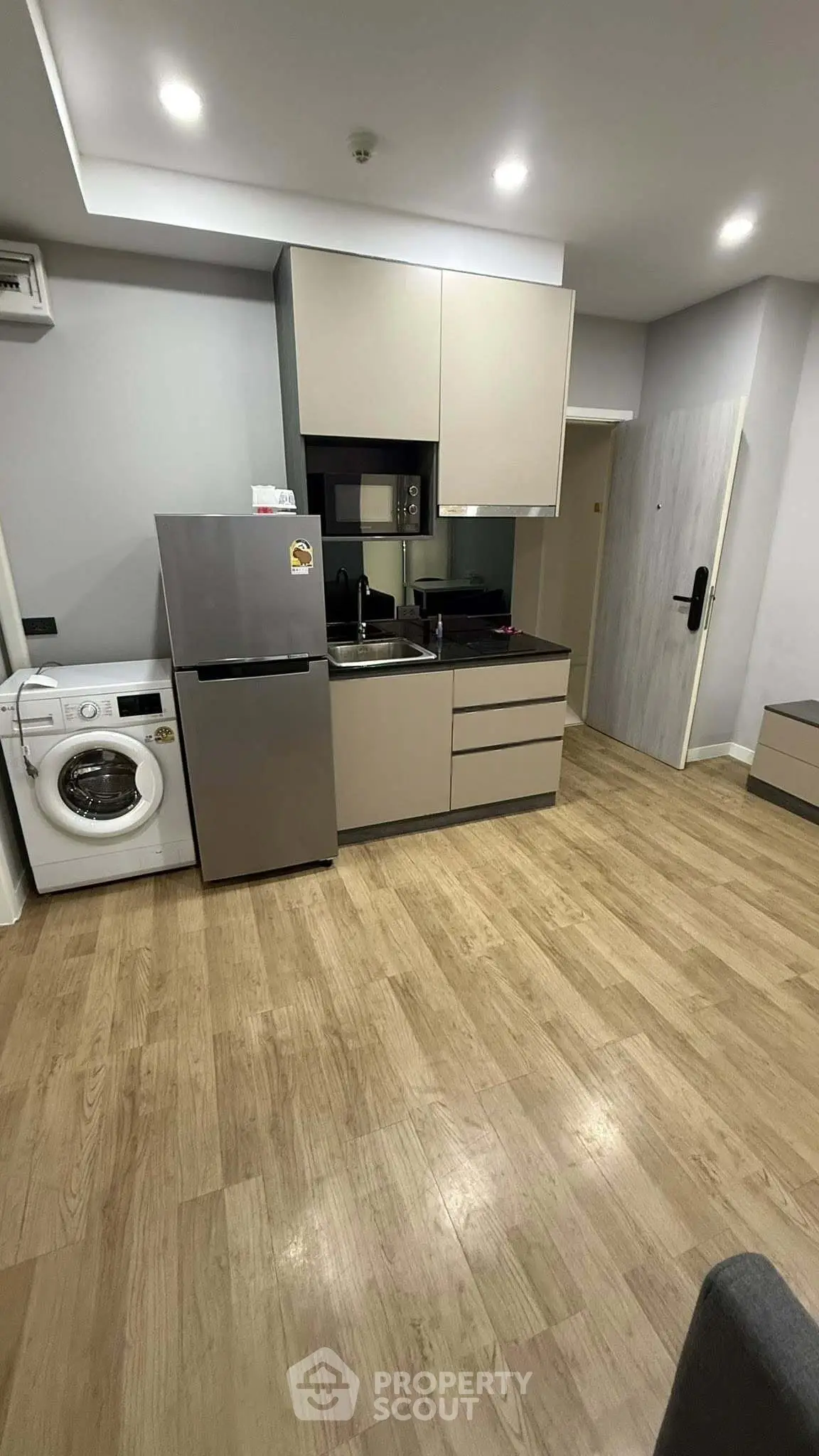 Modern kitchen with sleek cabinetry, stainless steel fridge, and in-unit washing machine.