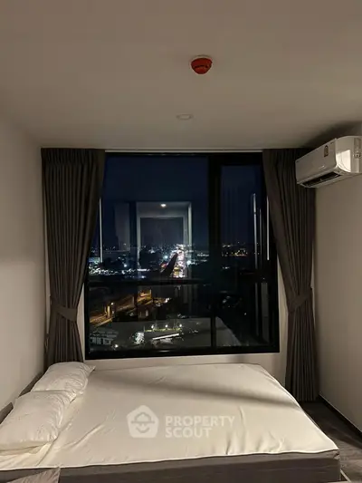 Modern bedroom with large window offering stunning city night view, featuring minimalist decor and air conditioning.